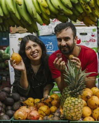 Group tasting tropical fruits like lulo, guanabana, and pitaya at Medellin market