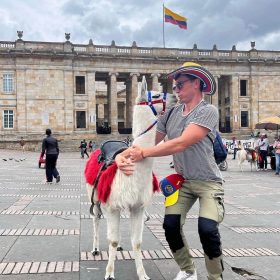 Traveler with llama in Bogotá’s Plaza de Bolívar wearing sombrero vueltiao and Colombian flag.