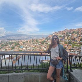 Woman at Medellín viewpoint with panoramic cityscape and blue sky in the background.