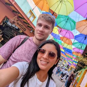 Couple smiling under colorful umbrella street in Guatapé, Antioquia.