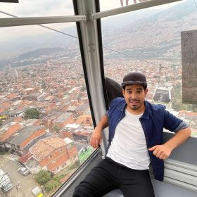 Man riding Medellín’s famous Metrocable with panoramic city view in the background.