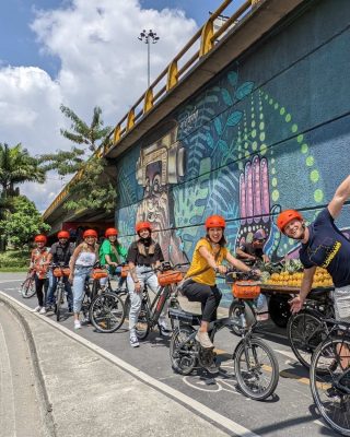 E-bike riders passing colorful murals and streets in Medellín’s El Poblado